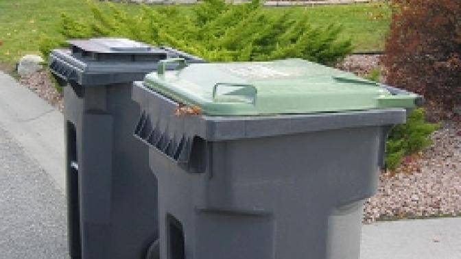 Compost bin and garbage bins set outside on a curb.