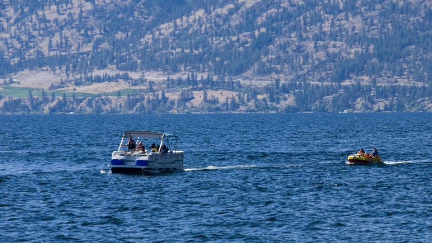 Boats floating on lake. There are mountains in the background.