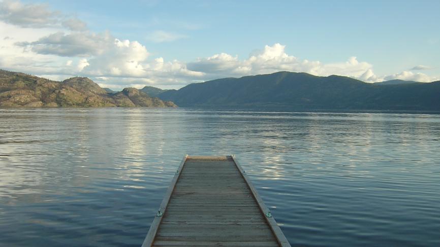 Pier leading to lake. There are mountains in the background.