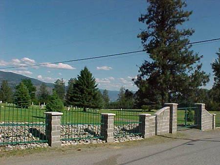 Peachland cemetery gated entrance. There is an iron gate with stone pillars that lead into the cemetery.