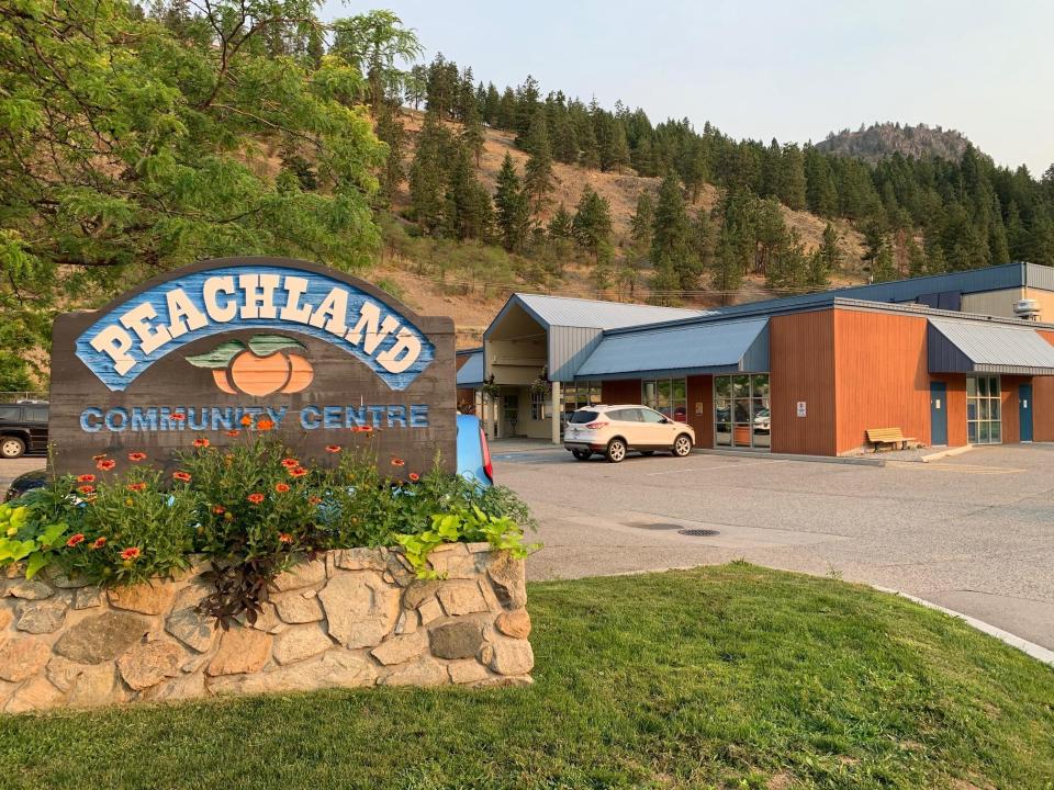 Exterior of Peachland Community Centre. There is signage for the community centre and there are mountains in the background.