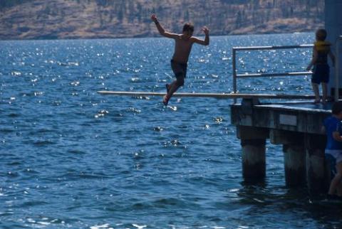 Person jumping into water from a dock.