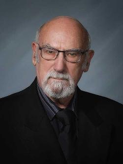 Councillor Terry Condon headshot. There is a stern looking man with glasses and a dark suit.